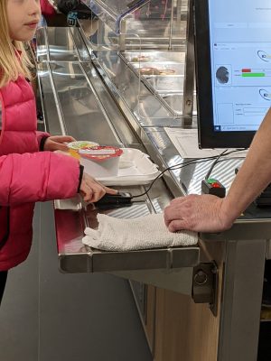 little girl using a finger reader to checkout her lunch